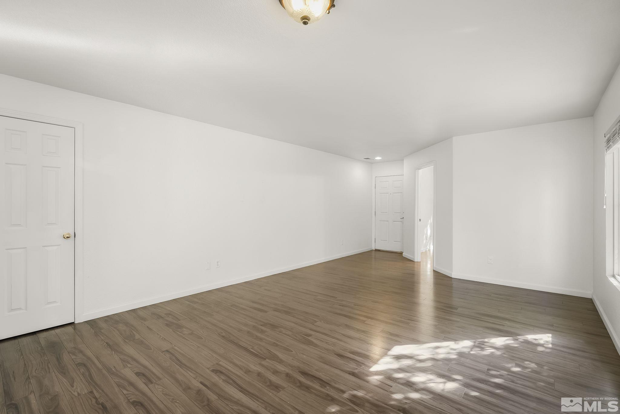 7859 Tulear Street Reno, NV 89506 - Photo 5 of 19 a view of an empty room with wooden floor and a window