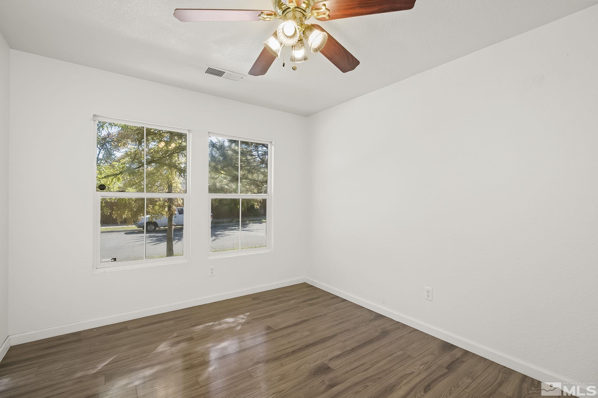 7859 Tulear Street Reno, NV 89506 - Photo 6 of 19 a view of an empty room with wooden floor and a window