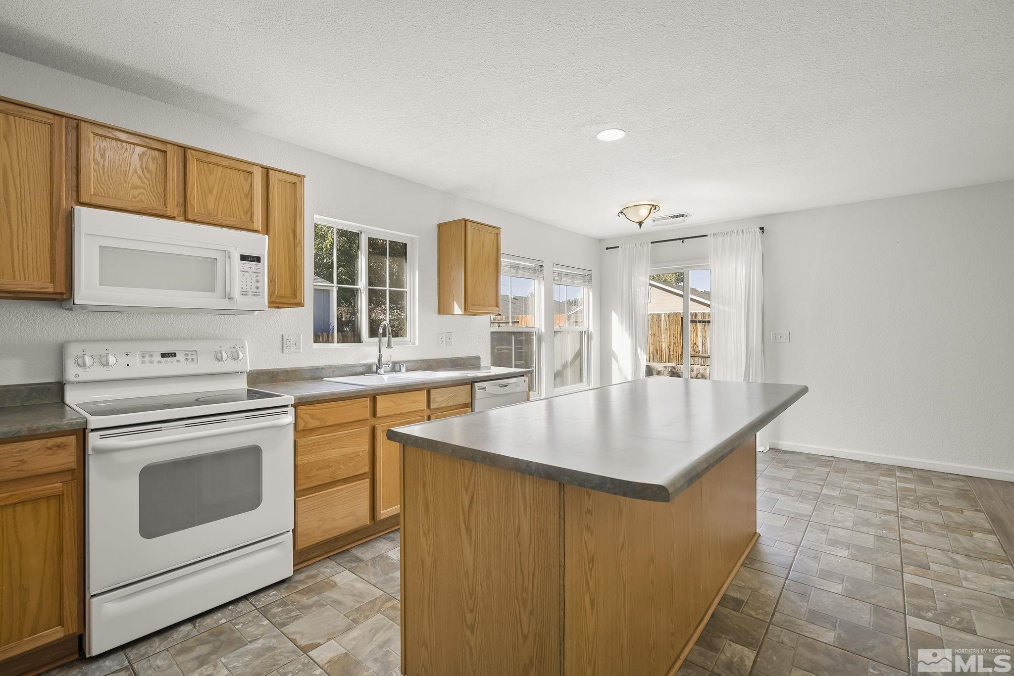 7859 Tulear Street Reno, NV 89506 - Photo 9 of 19 a kitchen with stainless steel appliances granite countertop a sink stove and refrigerator
