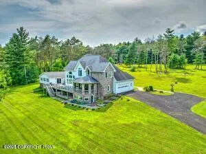 a view of a house with a big yard and large trees