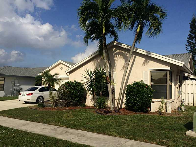 21080 Woodspring Avenue Boca Raton, FL 33428 - Photo 2 of 20 a view of a white house with a big yard plants and palm trees
