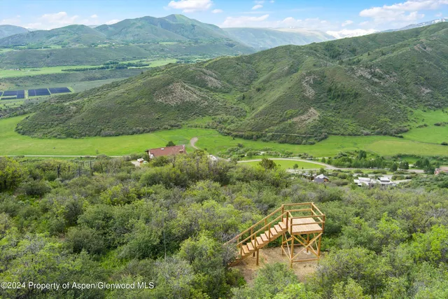 a aerial view of a houses with a lush green hillside