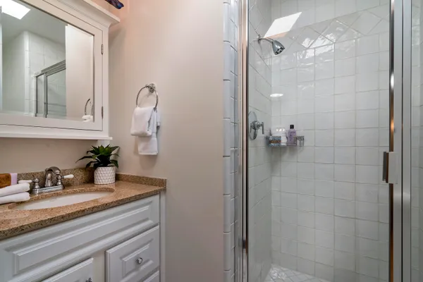 a bathroom with a granite countertop sink a mirror and shower
