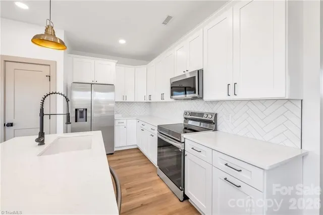 a kitchen with stainless steel appliances a sink a stove a refrigerator cabinets and a window