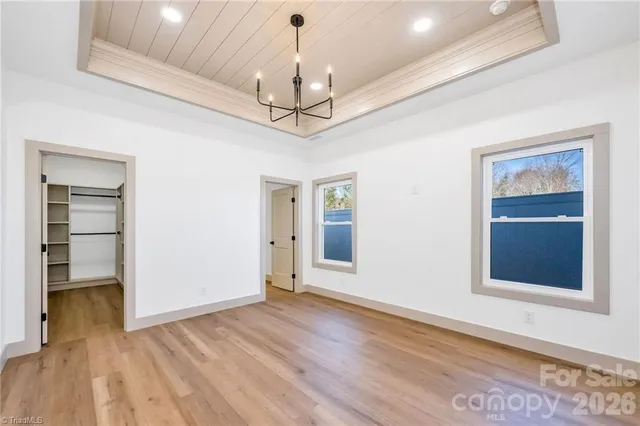 a view of a livingroom with a chandelier fan and wooden floor
