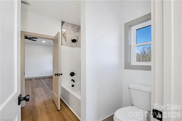 a bathroom with a toilet a sink a mirror and shower