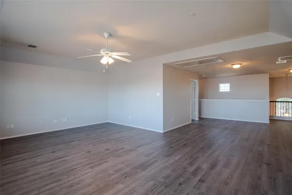 a view of an empty room with wooden floor and a ceiling fan