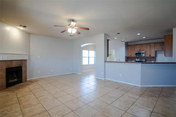 a view of an empty room with chandelier fan and fire place