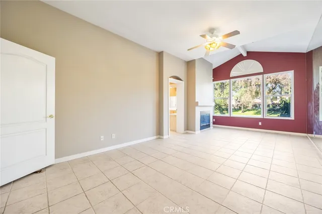 a view of an empty room with window and chandelier fan