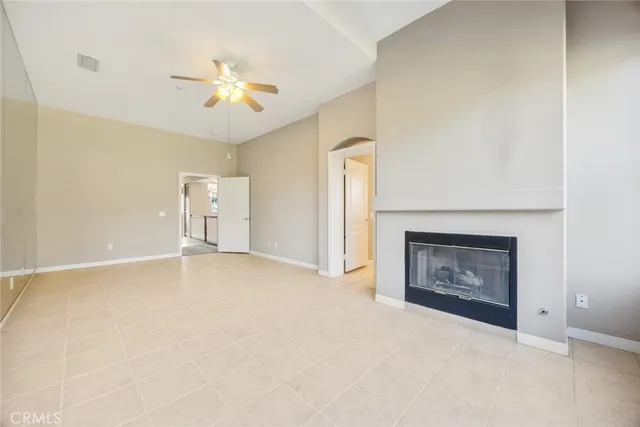 an empty room with chandelier fan and fireplace