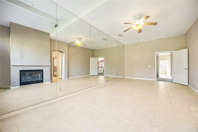 an empty room with a fireplace and chandelier fan