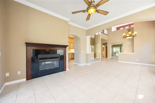 a view of an empty room with a fireplace and a chandelier fan