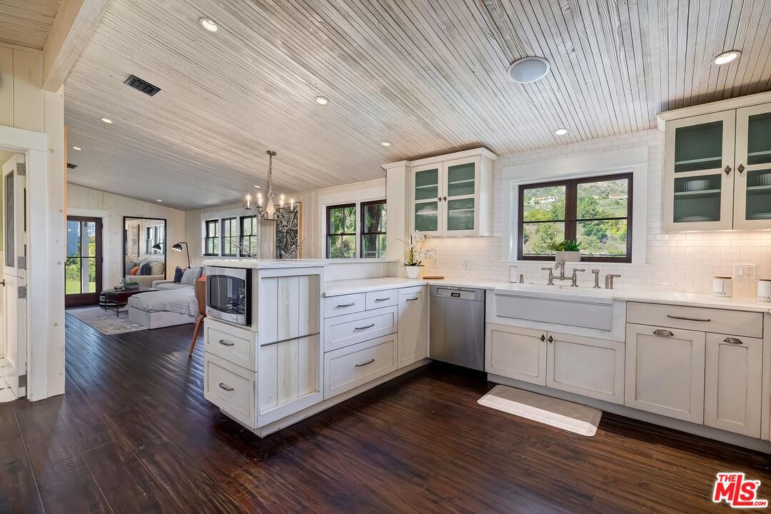 13240 Chalon Road Los Angeles, CA 90049 - Photo 15 of 46 a large white kitchen with window and white cabinets