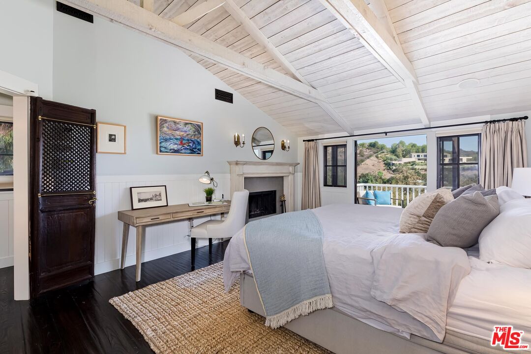 13240 Chalon Road Los Angeles, CA 90049 - Photo 20 of 46 a large bedroom with a bed and a fireplace
