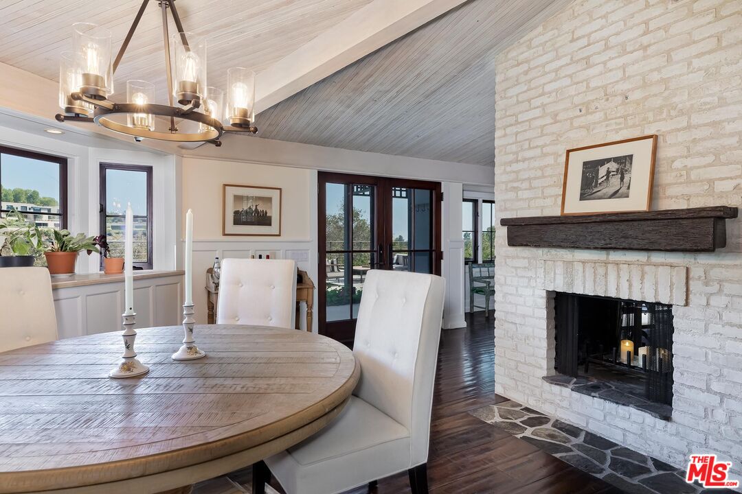 13240 Chalon Road Los Angeles, CA 90049 - Photo 8 of 46 a dining room with furniture a fireplace and wooden floor