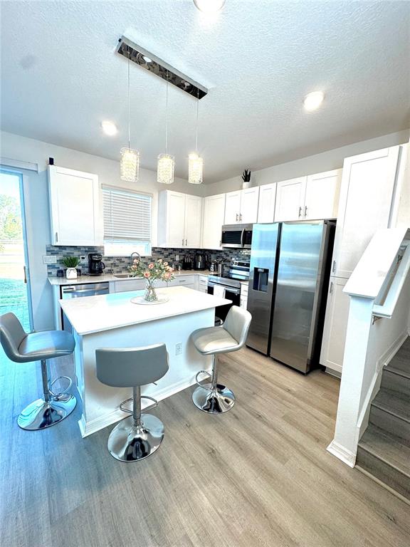 1301 Wycliffe Way St. Cloud, FL 34771 - Photo 6 of 50 a room with stainless steel appliances a dining table wooden floor and a view of kitchen