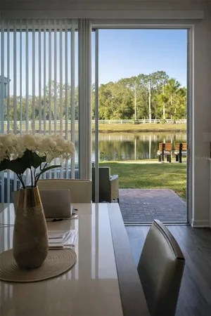 a room with stainless steel appliances a dining table wooden floor and a view of kitchen