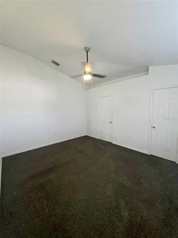 an empty room with a ceiling fan and window