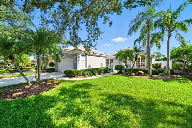 a view of a house with a big yard and palm trees