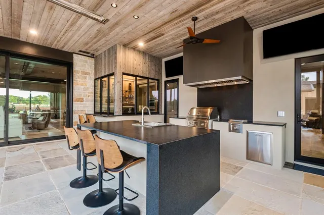 a dining hall with stainless steel appliances kitchen island granite countertop a table chairs and a refrigerator