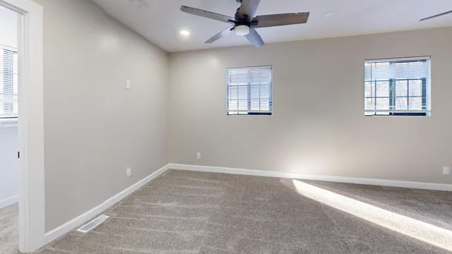 an empty room with windows and fan