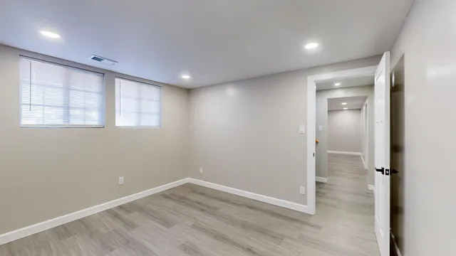 an empty room with wooden floor and windows