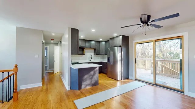 a large kitchen with a center island wooden floor stainless steel appliances and windows