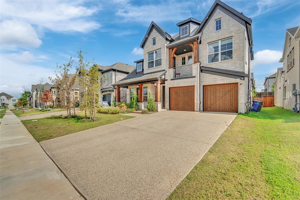 3520 Helios Lane Corinth, TX 76208 - Photo 1 of 37 Contemporary stone facade residence featuring a covered entry porch, second-story balcony with metal railing, two wood-finish garage doors, and a concrete driveway