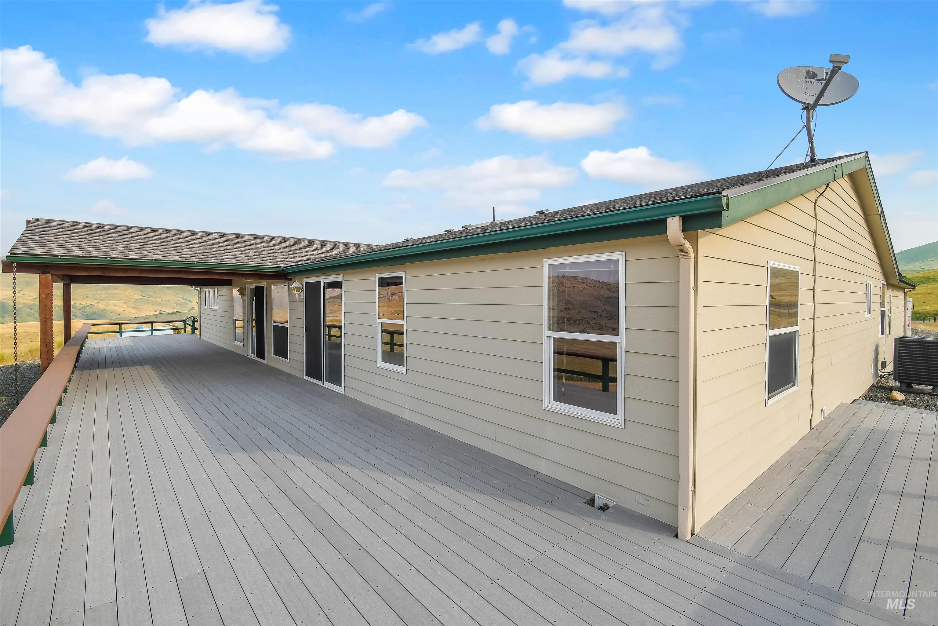 11375 Timber Butte Road Sweet, ID 83670 - Photo 38 of 49 Expansive composite deck featuring a partial overhang, tan siding, multiple windows, and sliding glass doors