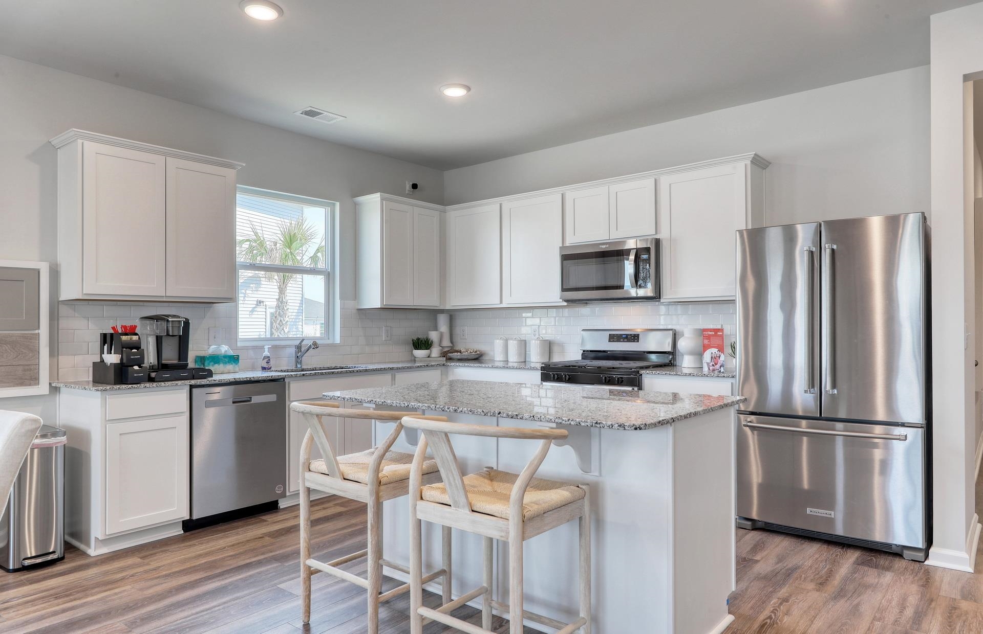 803 Laconic Drive Myrtle Beach, SC 29588 - Photo 10 of 21 Kitchen with stainless steel appliances, white cabinets, a breakfast bar area, light stone countertops, and a kitchen island