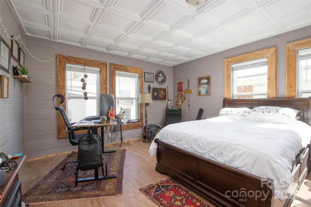 a bedroom with a bed a table and a large mirror next to a window