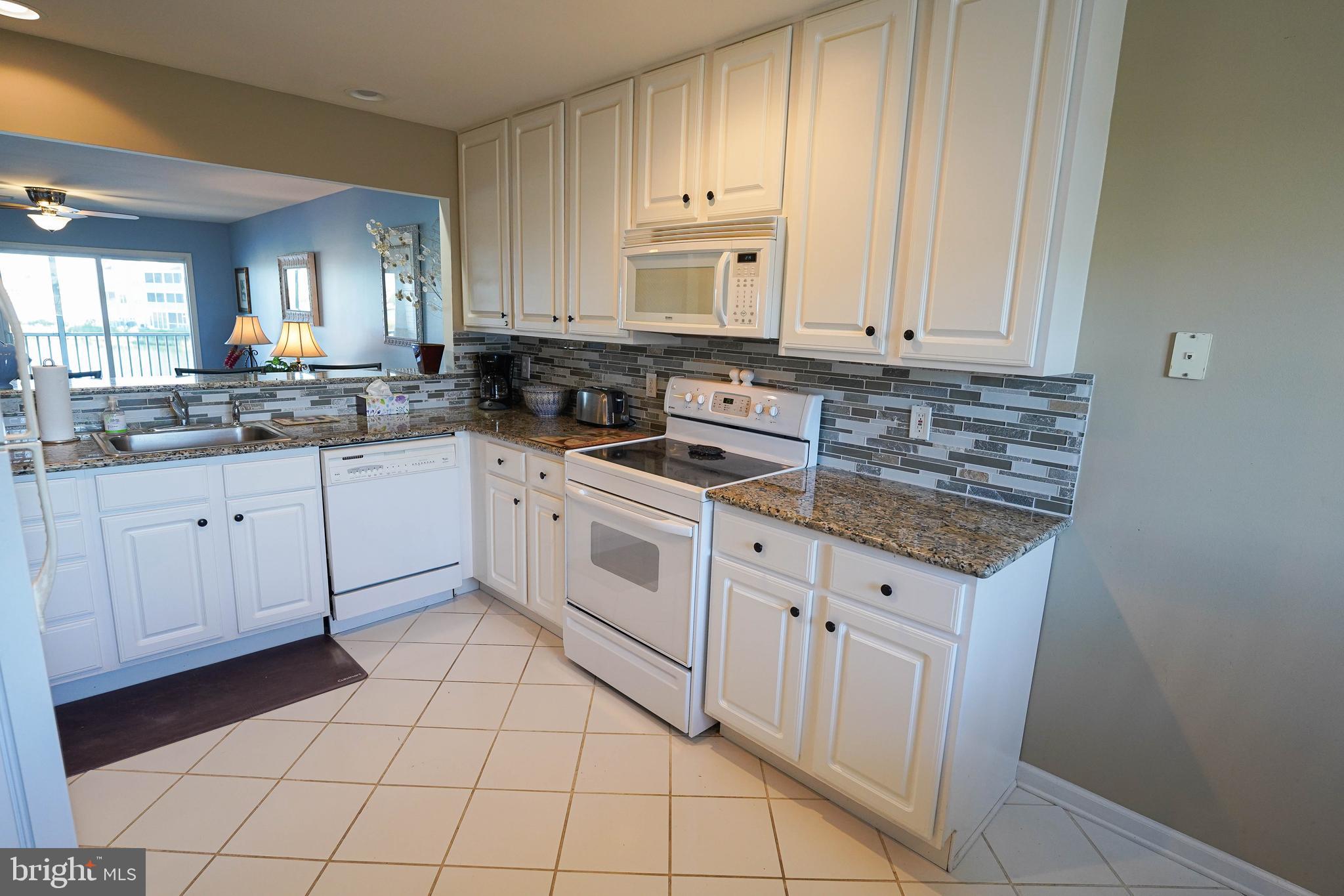 37182 Harbor Drive, Unit 264 Ocean View, DE 19970 - Photo 28 of 55 a kitchen with granite countertop white cabinets white stainless steel appliances with a sink and dishwasher