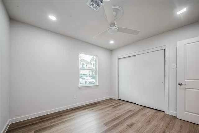 an empty room with wooden floor and ceiling fan