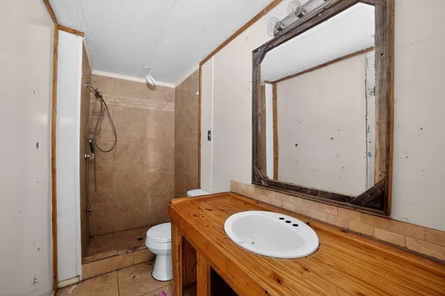 a bathroom with a granite countertop sink toilet a mirror and shower