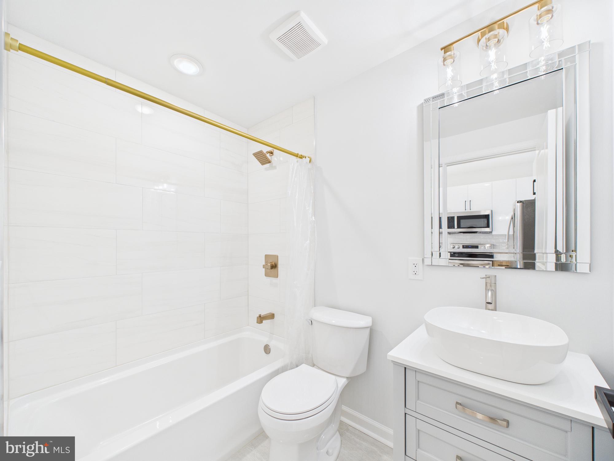 1326 Grove Street, Unit 4 Philadelphia, PA 19146 - Photo 8 of 14 a bathroom with a sink a mirror a toilet and bathtub