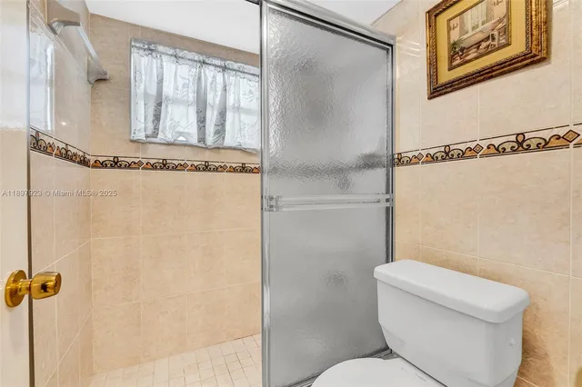 a white toilet sitting next to a shower