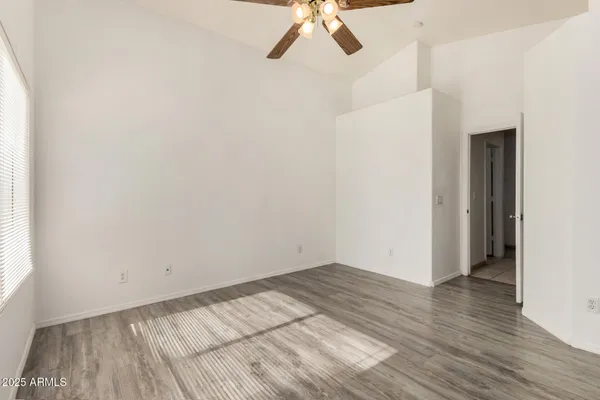 an empty room with a hardwood and ceiling fan