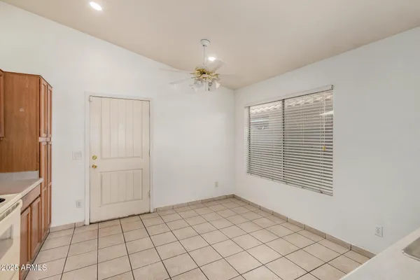 a view of an empty room with window and chandelier fan