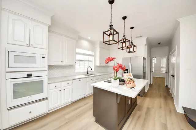 a kitchen with a sink dishwasher a stove and white cabinets with wooden floor