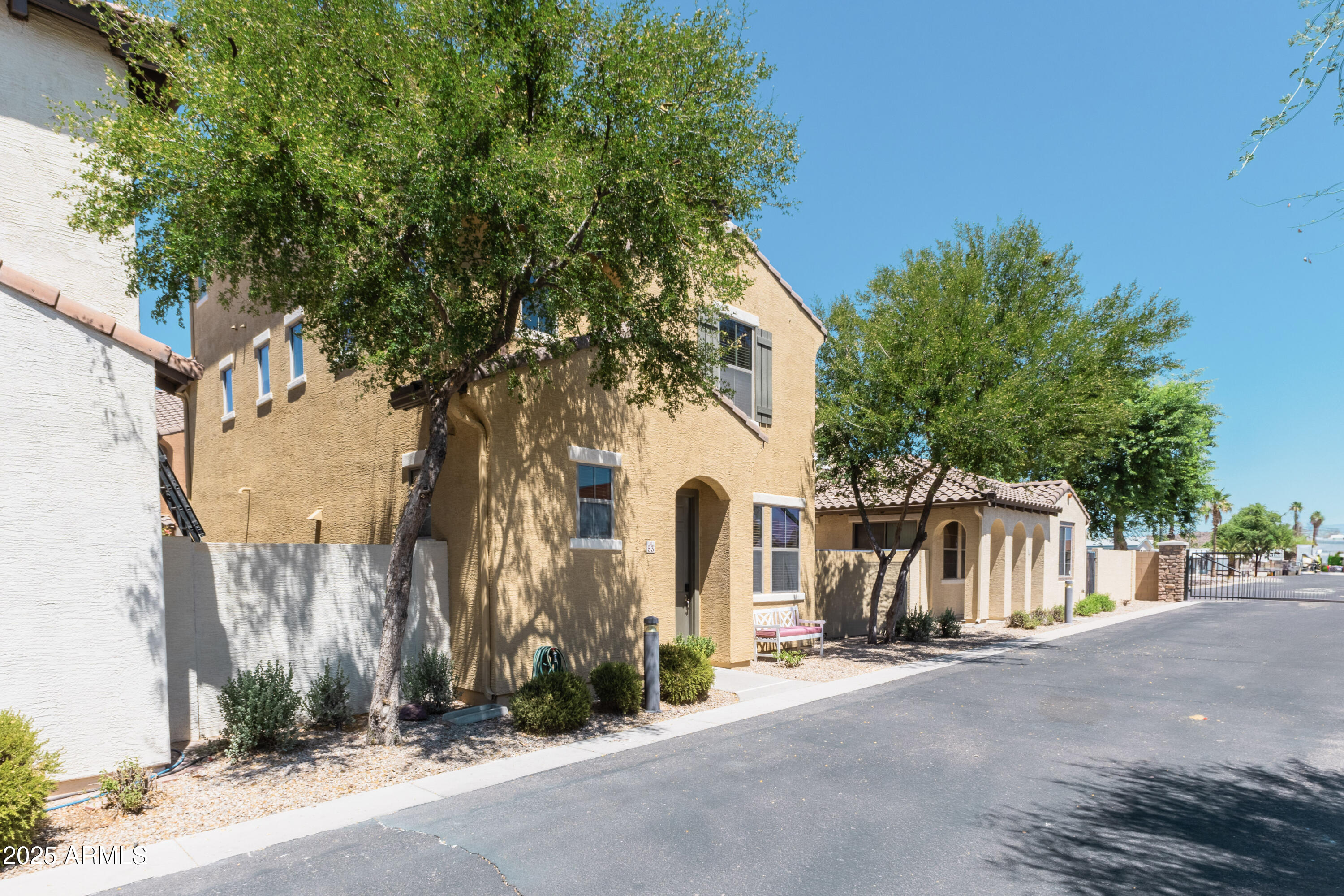 451 South Hawes Road, Unit 53 Mesa, AZ 85208 - Photo 2 of 37 a view of a white house with a large tree and wooden fence
