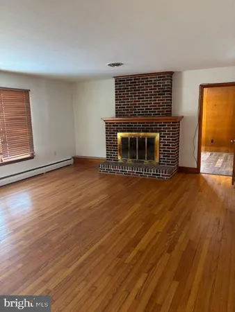 a view of a livingroom with wooden floor and a fireplace