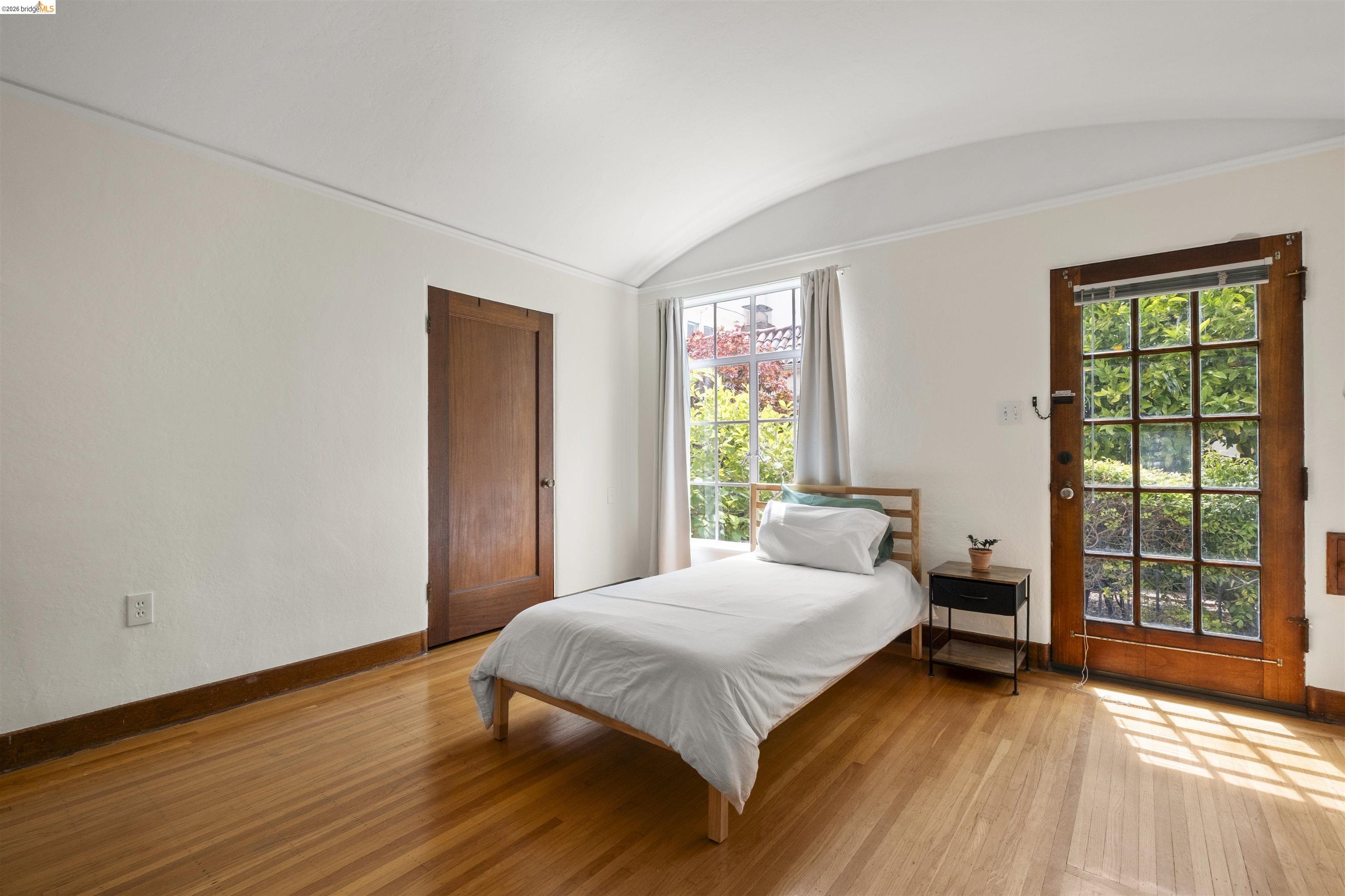 2444 Virginia Street, Unit B Berkeley, CA 94709 - Photo 30 of 39 Hardwood flooring throughout featuring a wood-panel door, multiple windows, and an arched ceiling detail