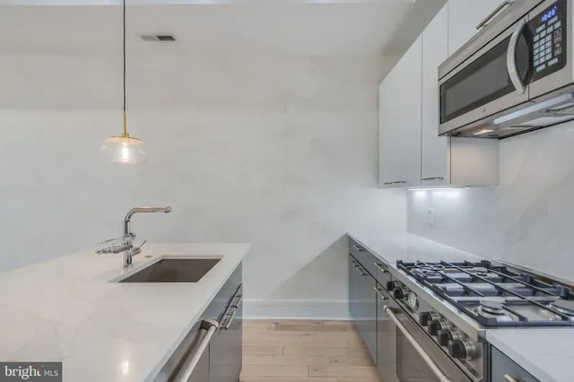 a kitchen with stainless steel appliances a refrigerator a sink a stove a microwave and island