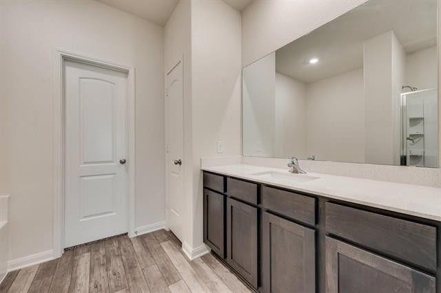 13609 Mineral Road Ponder, TX 76259 - Photo 21 of 21 Bathroom featuring wood-finish flooring, a double vanity with a light-toned countertop and integrated sinks, and a large wall-mounted mirror