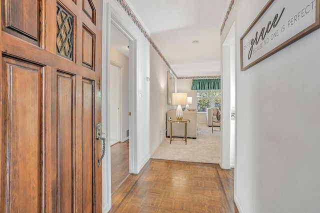 a view of a hallway with a view of a livingroom with wooden floor and a hallway