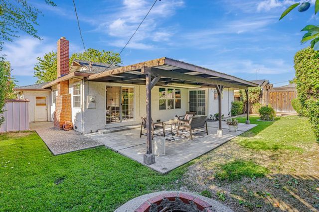 a view of a chair and table in backyard of the house
