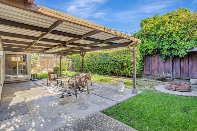 a view of a backyard with table and chairs potted plants and a palm tree