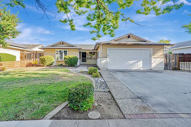 a front view of a house with a yard and potted plants