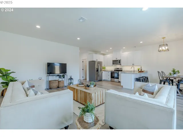 a living room with furniture a flat screen tv and kitchen view