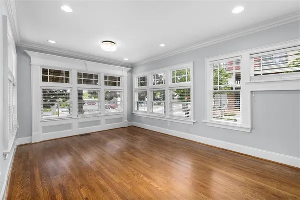 a view of an empty room with a window and wooden floor
